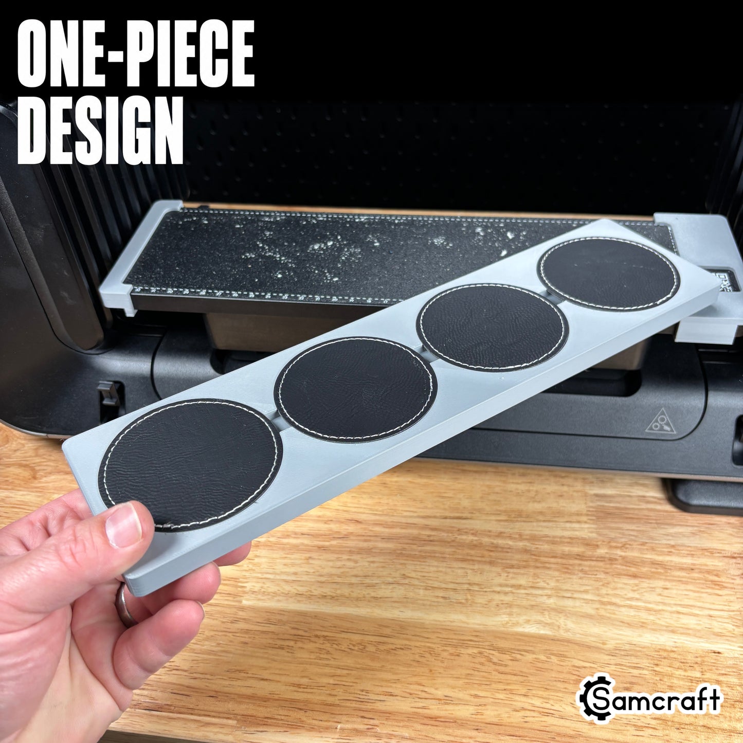 Round Patch Jig for the eufyMake E1 — hand holding the gray one-piece 3D-printed tray loaded with four round black leather patches with white stitching in their circular molded pockets, showing the solid single-piece design.
