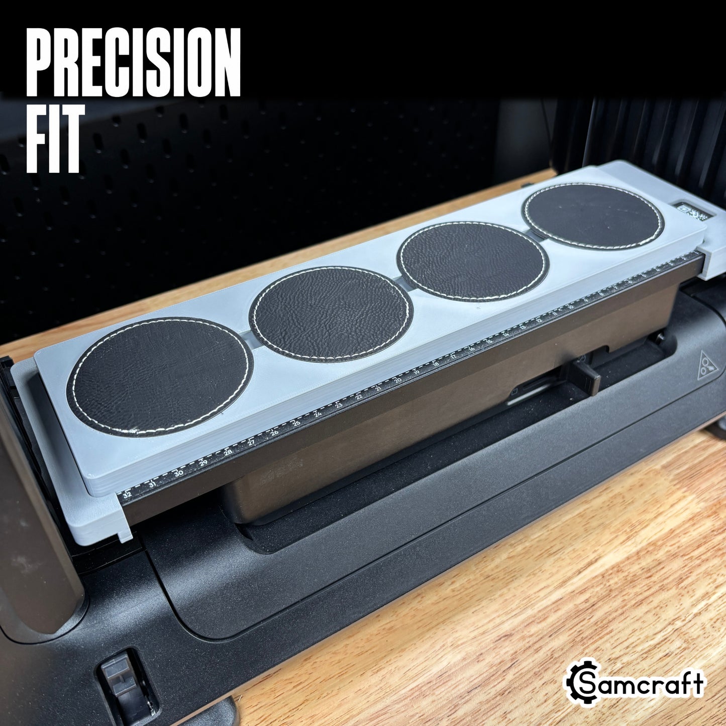 Round Patch Jig for the eufyMake E1 — close-up of round black leather patches with white stitched edges sitting flush in the circular recessed pockets of the gray 3D-printed tray, with the built-in measurement ruler visible, showing the precision fit.