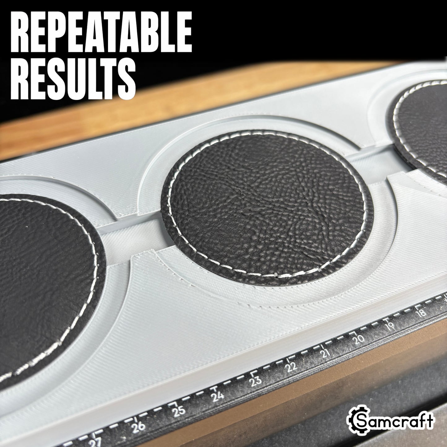 Round Patch Jig for the eufyMake E1 — angled close-up of round black leather patches with white stitching held in the circular pockets of the gray 3D-printed tray with built-in alignment ruler, positioned for repeatable, consistent print results.