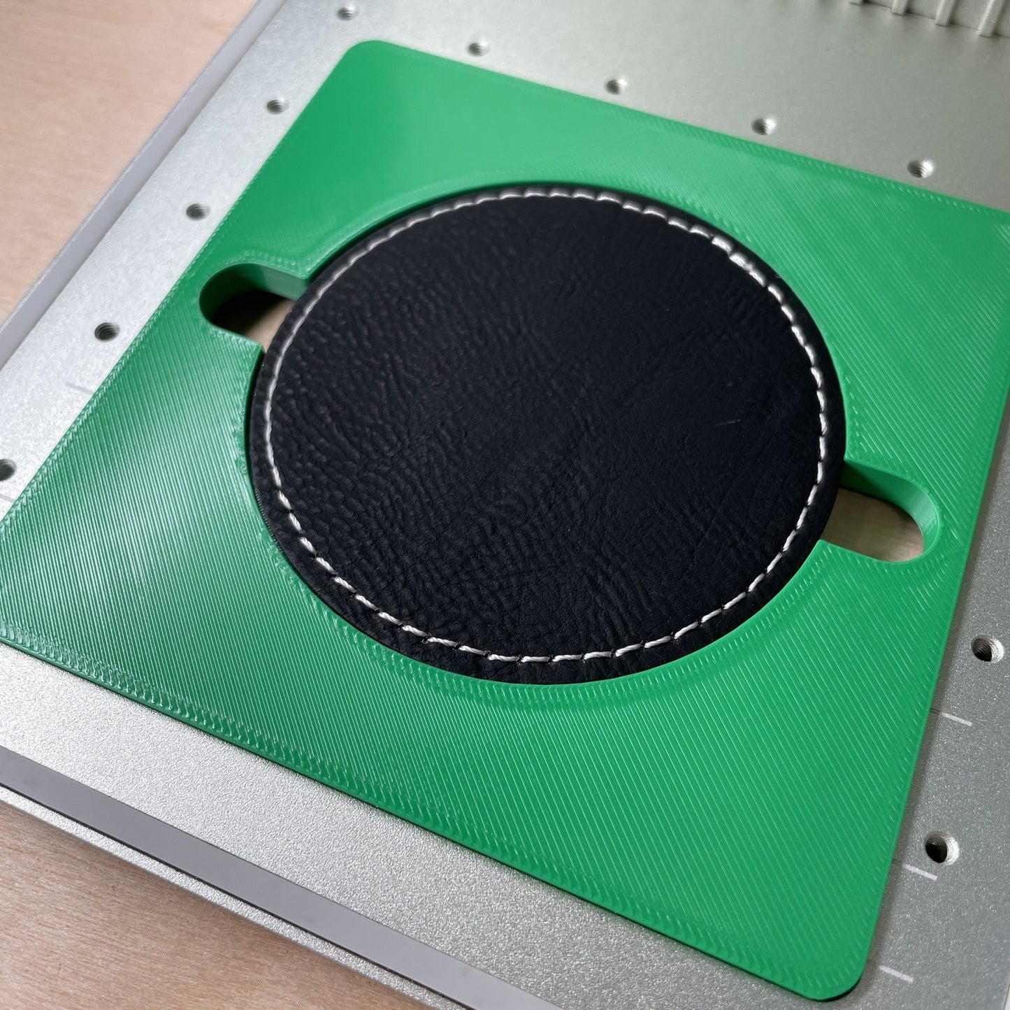 Samcraft round patch jig in an xTool F1 laser bed, holding a large black leatherette round patch.
