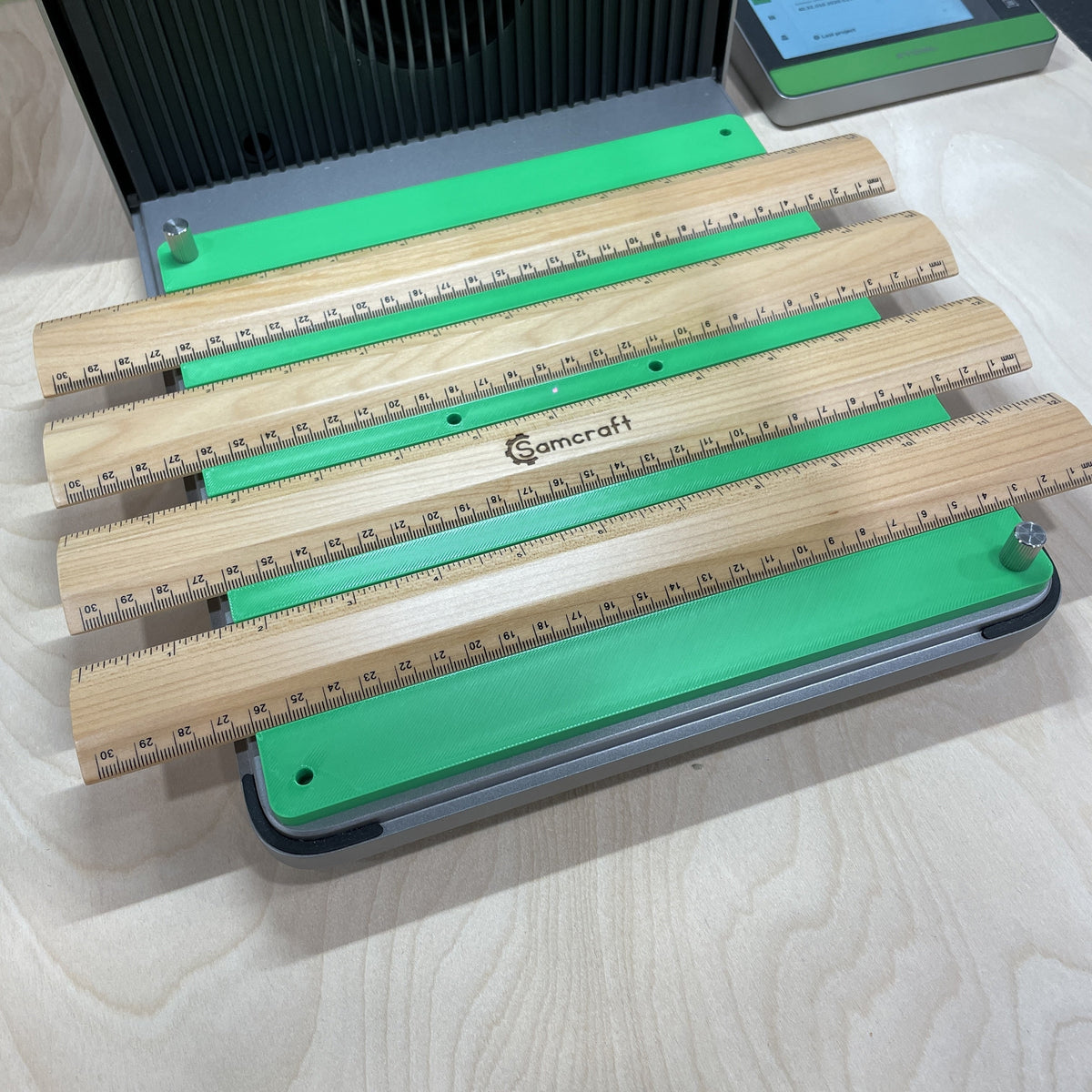 Samcraft green ruler jig in an xTool F1 Ultra laser bed, holding wooden rulers end to end.