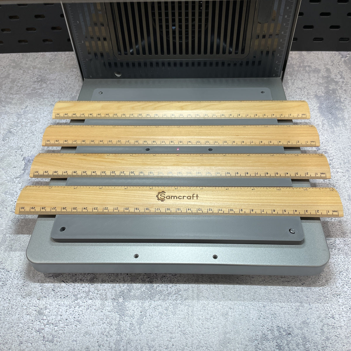 Samcraft ruler jig on the xTool F2 Ultra bed, holding wooden rulers.