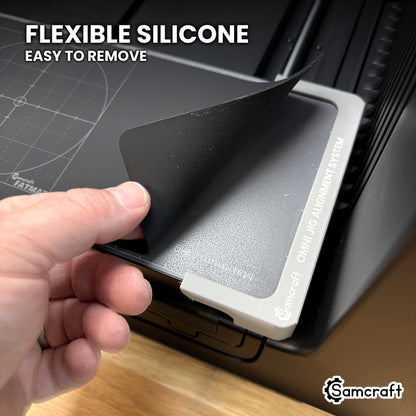 Flexible silicone Samcraft Jig Size FatMat being lifted out of the xTool Omni alignment system by hand.
