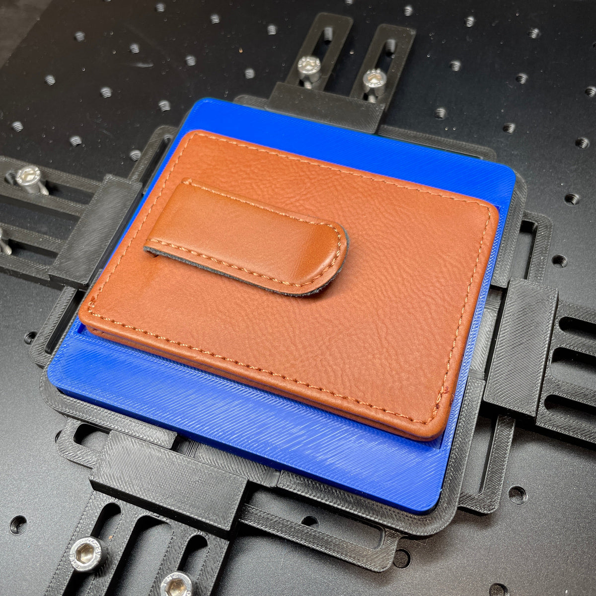 Samcraft blue slim wallet jig on a ComMarker laser bed, holding a tan leather wallet.