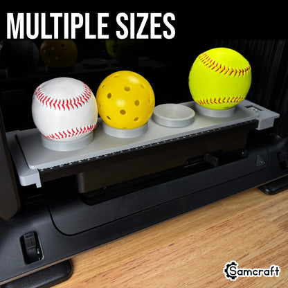 Sports Ball Jig for the eufyMake E1 — gray 3D-printed tray on the printer bed holding a baseball, pickleball, and softball in multiple ring-holder sizes with built-in alignment ruler.