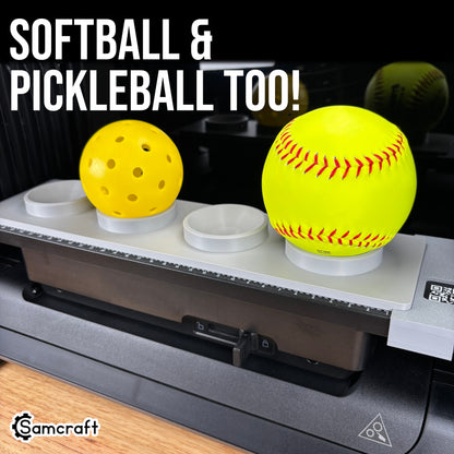 Sports Ball Jig for the eufyMake E1 — gray 3D-printed tray holding a yellow pickleball and a yellow softball in cupped ring holders on the printer bed, showing it fits softballs and pickleballs too.