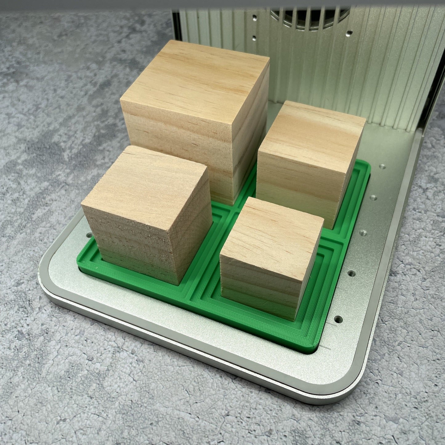 Samcraft medium square block jig in an xTool F1 laser bed, cradling four wooden blocks of different sizes.