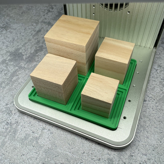 Samcraft medium square block jig in an xTool F1 laser bed, cradling four wooden blocks of different sizes.