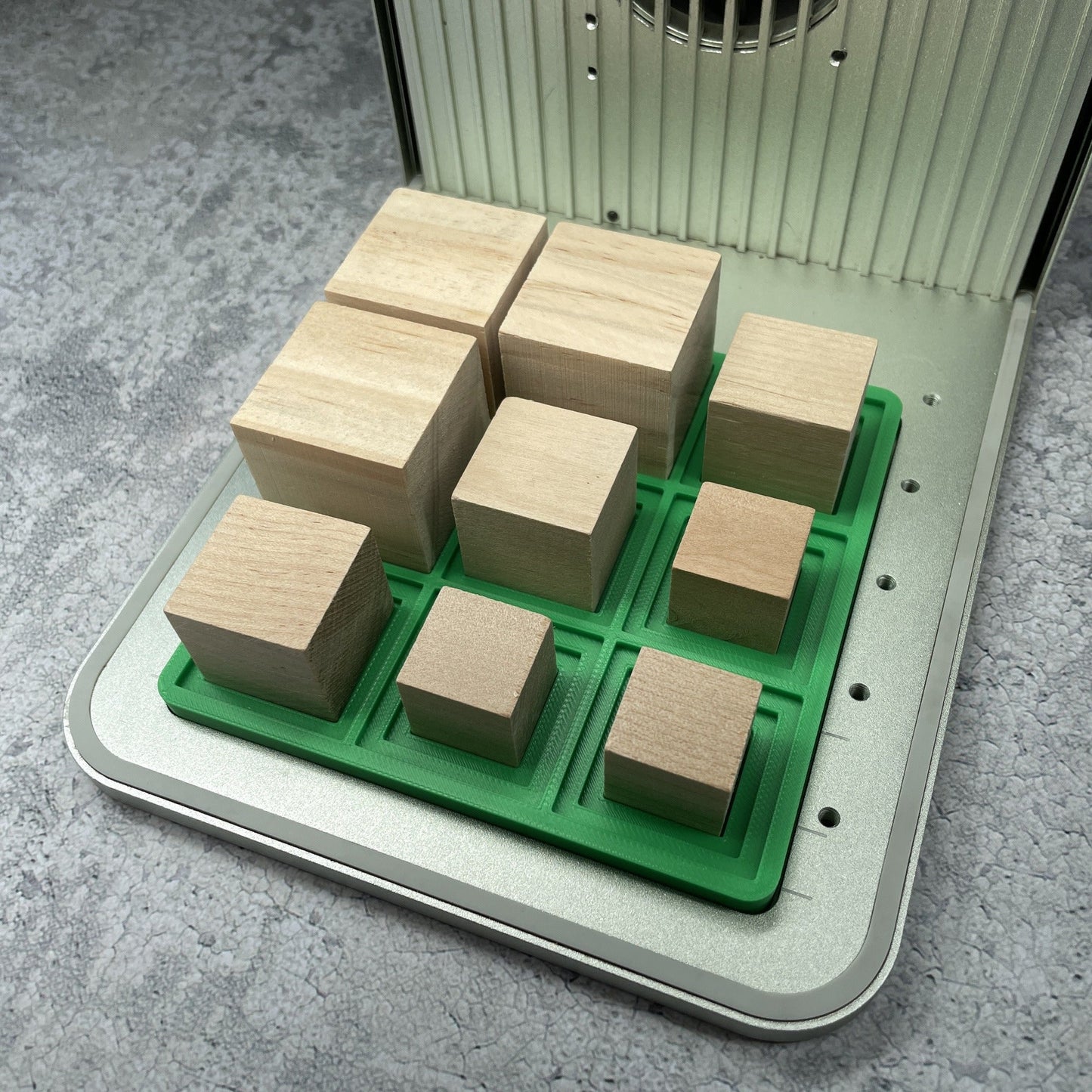 Samcraft small square block jig in an xTool F1 laser bed, cradling wooden blocks in four sizes.