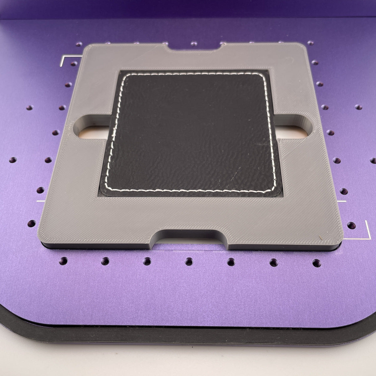 Samcraft square patch jig on the purple bed of a WeCreat Lumos, holding a square black leatherette patch.