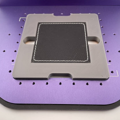 Samcraft square patch jig on the purple bed of a WeCreat Lumos, holding a square black leatherette patch.