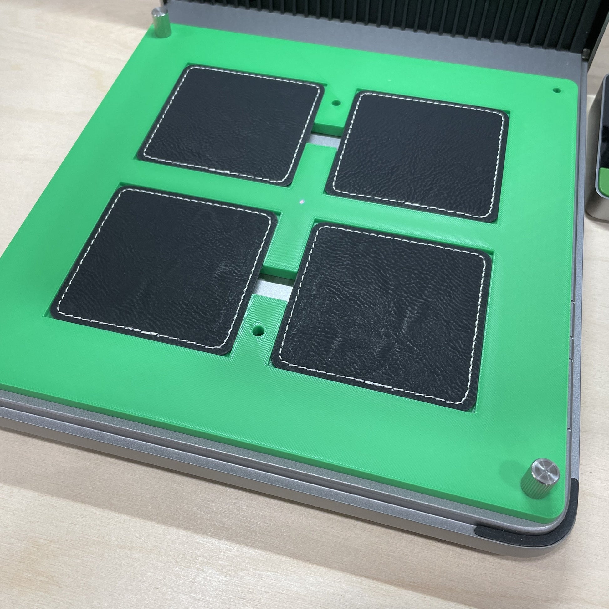 Samcraft green square patch jig in an xTool F1 Ultra laser bed, holding four black square leatherette patches.