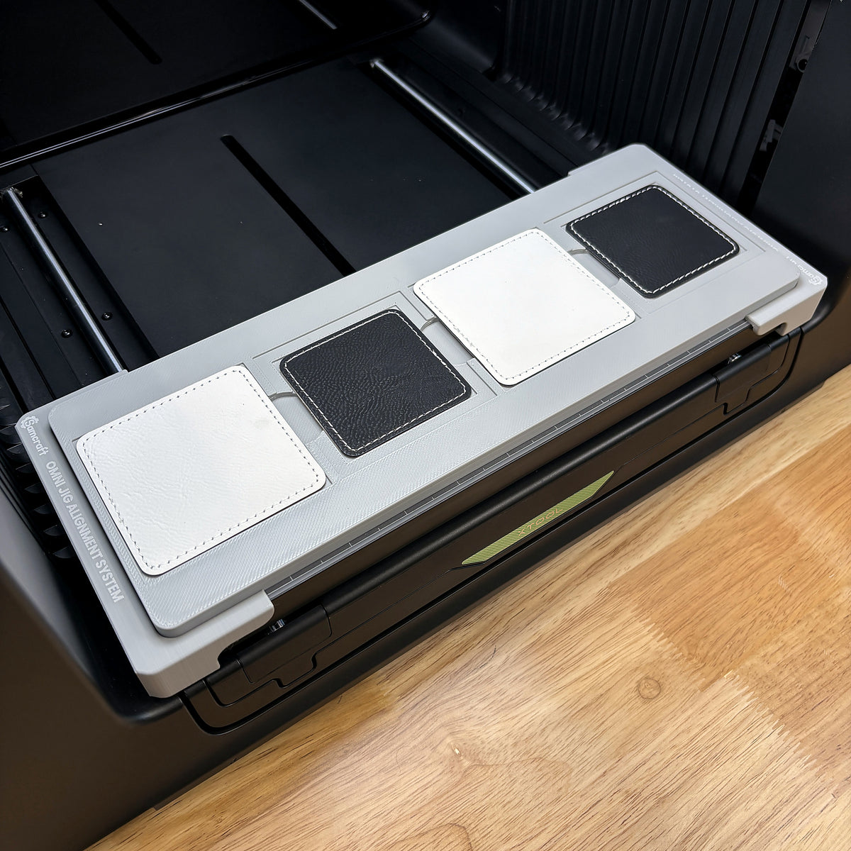 Samcraft square patch jig on the bed of an xTool Omni UV printer, loaded with four leatherette patches.