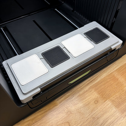 Samcraft square patch jig on the bed of an xTool Omni UV printer, loaded with four leatherette patches.