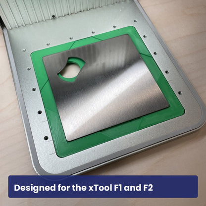 Samcraft stainless bottle opener jig seated in the xTool F1 base plate with an opener in the recess.