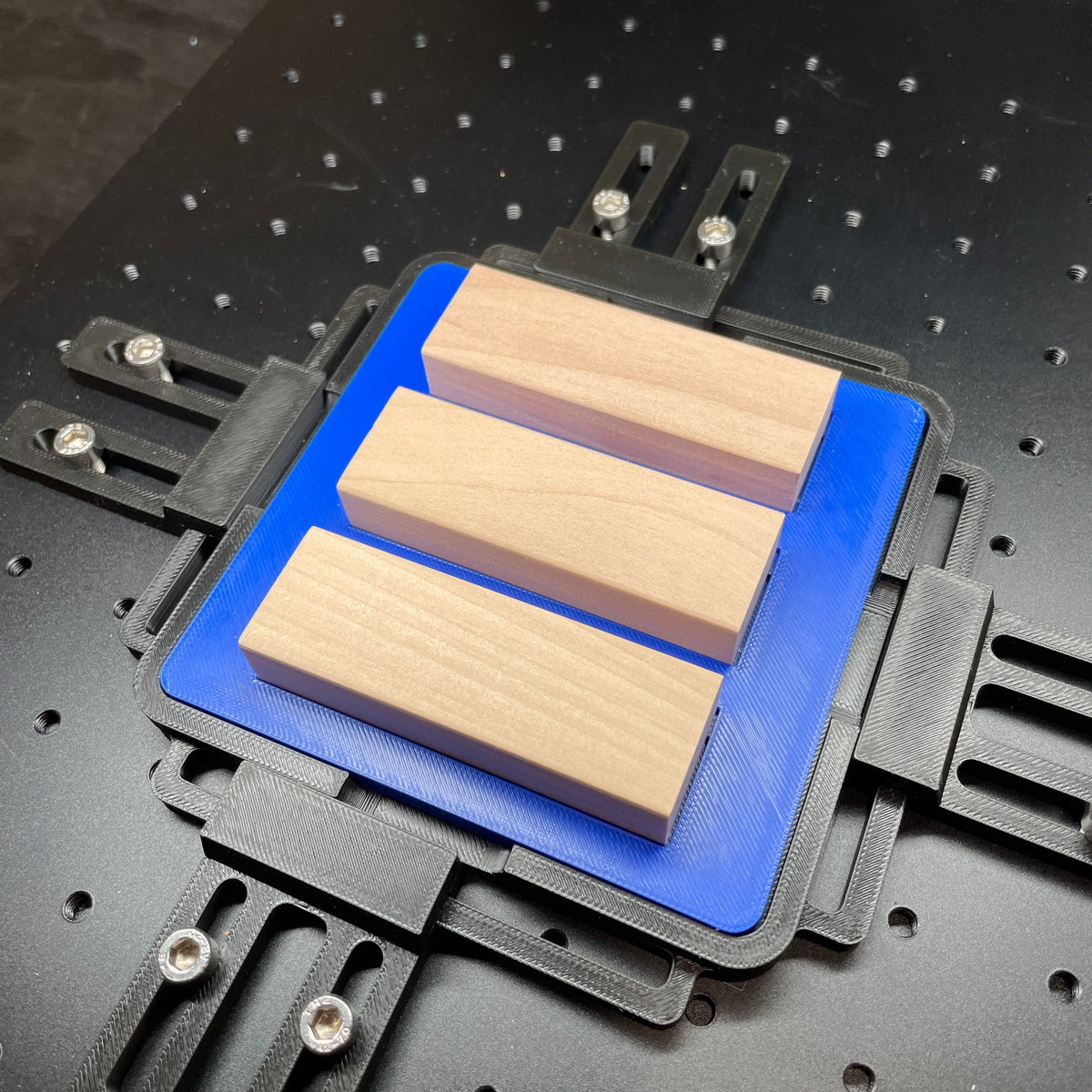 Samcraft blue tumbling tower game jig on a ComMarker laser bed, holding wooden game blocks.
