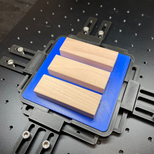 Samcraft blue tumbling tower game jig on a ComMarker laser bed, holding wooden game blocks.