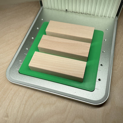 Samcraft tumbling tower game jig in an xTool F1 laser bed, holding three wooden game blocks.