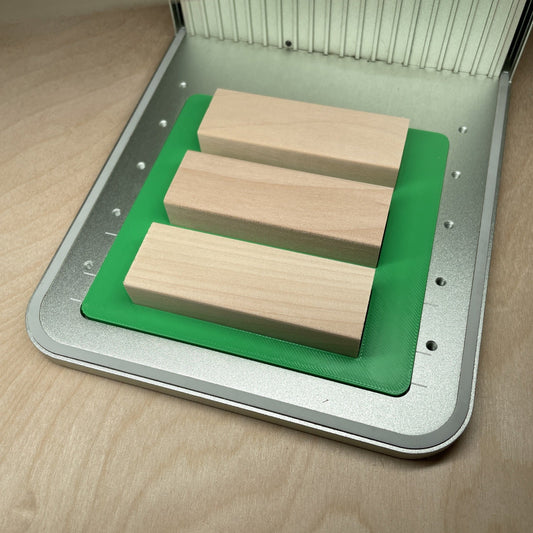 Samcraft tumbling tower game jig in an xTool F1 laser bed, holding three wooden game blocks.