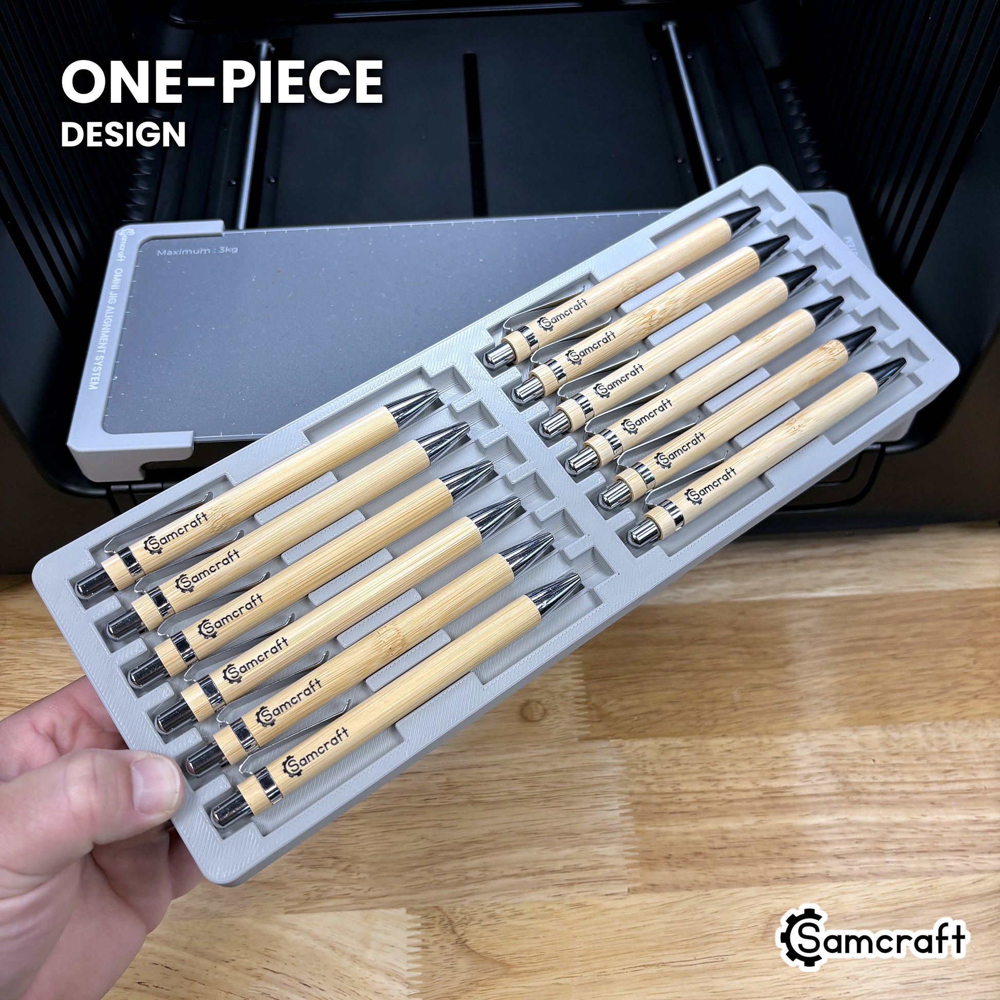 Hand holding the one-piece Samcraft 12 pen jig for the xTool Omni, twelve cradles in a single molded tray.
