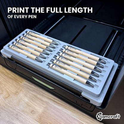 Twelve pens in the Samcraft xTool Omni jig with artwork printed along the full length of every barrel, end to end.