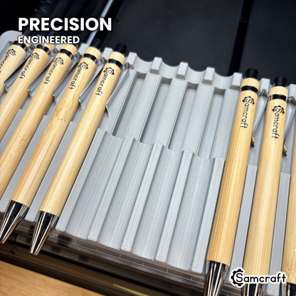 Close-up of the precision-engineered curved cradles in the Samcraft xTool Omni pen jig, with bamboo pens seated beside empty cradles.