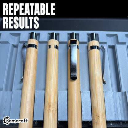 Close-up of bamboo pens with chrome clips seated in the Samcraft Universal Pen Jig's channels, demonstrating repeatable results and the alignment ruler on the eufyMake E1.