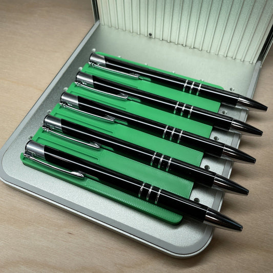 Samcraft universal pen jig in an xTool F1 laser bed, holding five black metal pens in its channels.