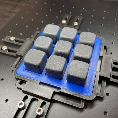 Samcraft blue whiskey stone jig on a ComMarker laser bed, holding grey stone cubes in a grid.