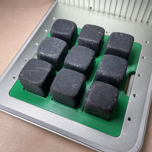 Samcraft whiskey stone jig in an xTool F1 laser bed, holding nine grey stone cubes in a three by three grid.