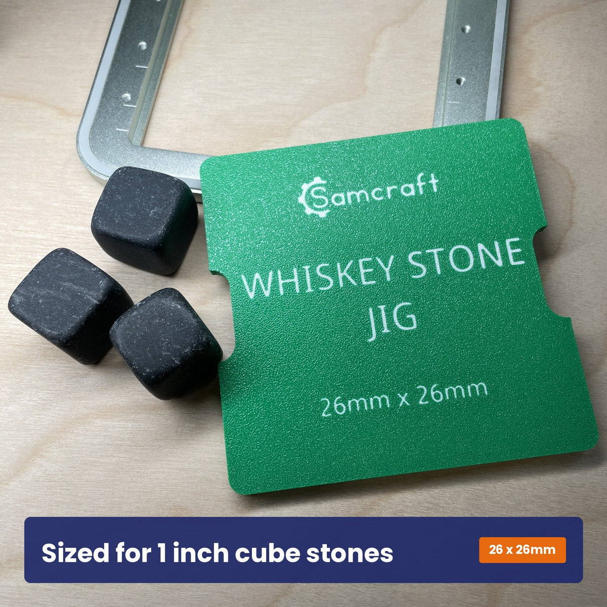 Samcraft whiskey stone jig shown beside two grey stone cubes, with the 26 by 26 millimetre size marked on the jig.