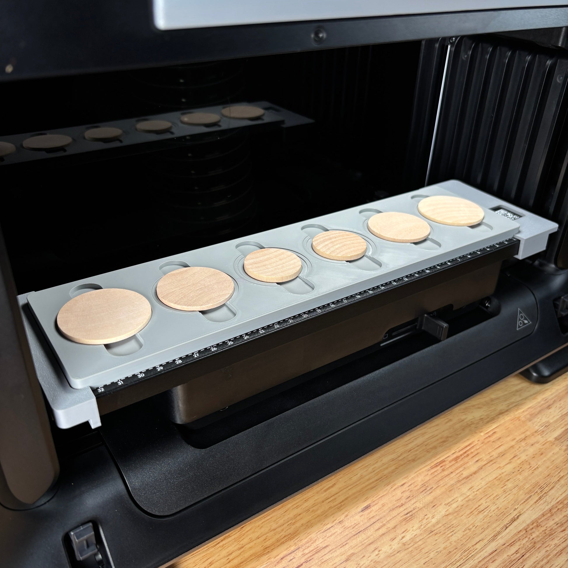 Samcraft wood coin jig on the eufyMake E1 print bed, holding round wooden coins in circular recesses.