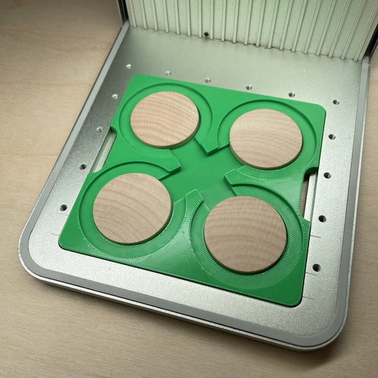 Samcraft wood coin jig in an xTool F1 laser bed, holding four blank wooden coins.