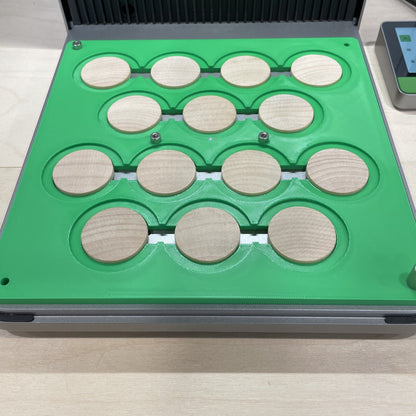 Samcraft green wood coin jig in an xTool F1 Ultra laser bed, holding a full grid of round wooden coins.
