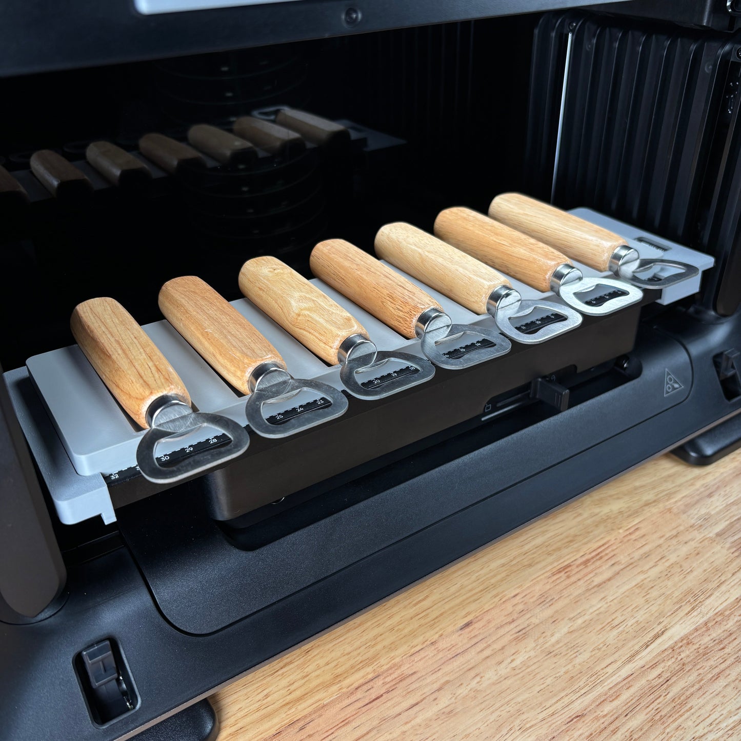 Samcraft wood handle bottle opener jig on the eufyMake E1 print bed, holding wood-handle bottle openers in channelled slots.