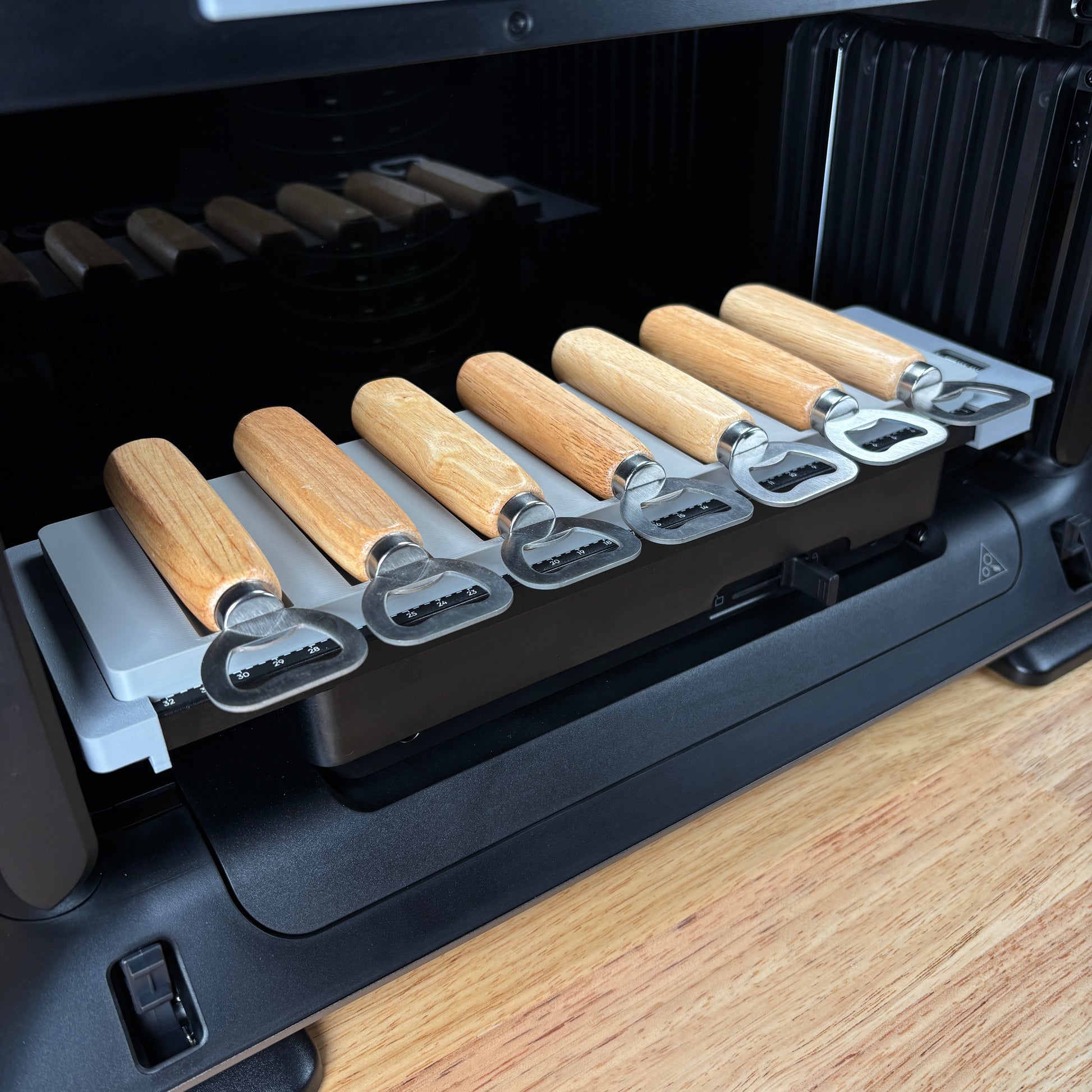 Samcraft wood handle bottle opener jig on the eufyMake E1 print bed, holding wood-handle bottle openers in channelled slots.