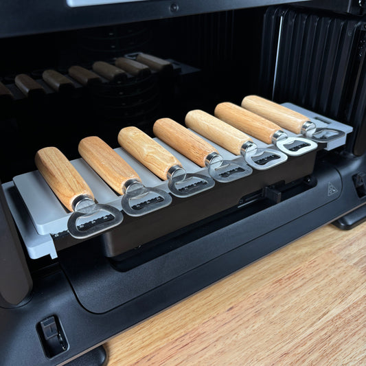 Samcraft wood handle bottle opener jig on the eufyMake E1 print bed, holding wood-handle bottle openers in channelled slots.