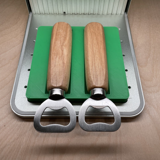 Samcraft green wood handle bottle opener jig in an xTool F1 laser bed, holding two wood-handled bottle openers.