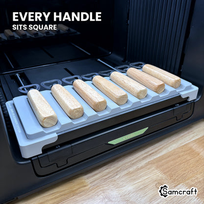 Every wood handle seated square in its own channel across the Samcraft xTool Omni jig, for consistent print placement.