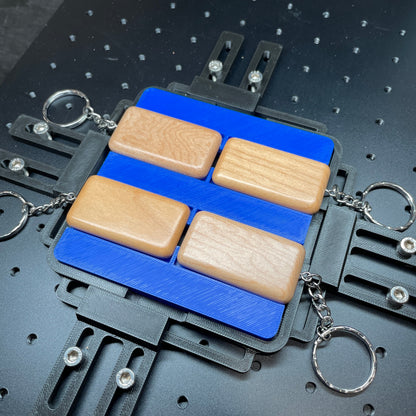Samcraft blue wood rectangle keychain jig on a ComMarker laser bed, holding wooden rectangle keychains on split rings.